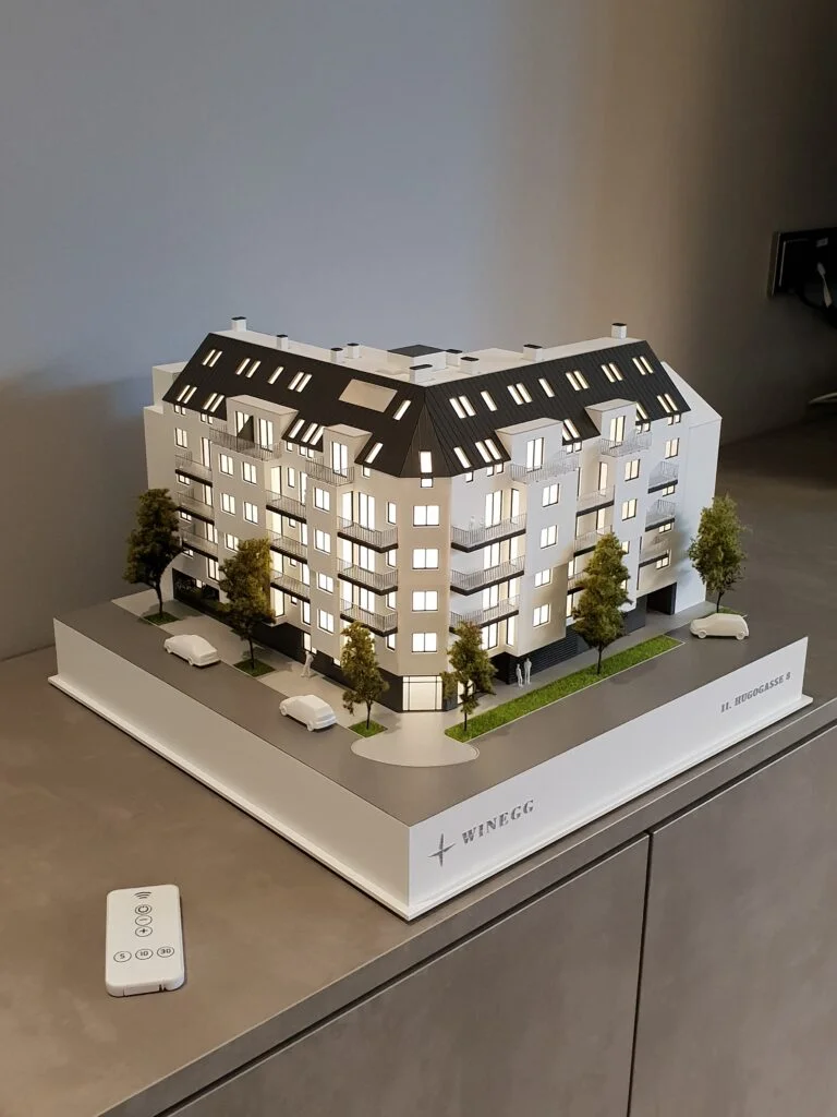 Architekturmodell Immobilien 1:100 – modernes Wohnhaus mit Balkonen, Begrünung und beleuchteten Innenräumen.