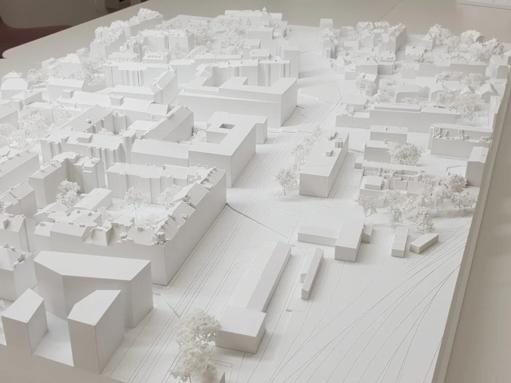Umgebungsmodell 1:1000 – Stadtquartier mit abstrahierten Baukörpern, Straßenführung, Bäumen und topografischen Linien für Wettbewerbe.