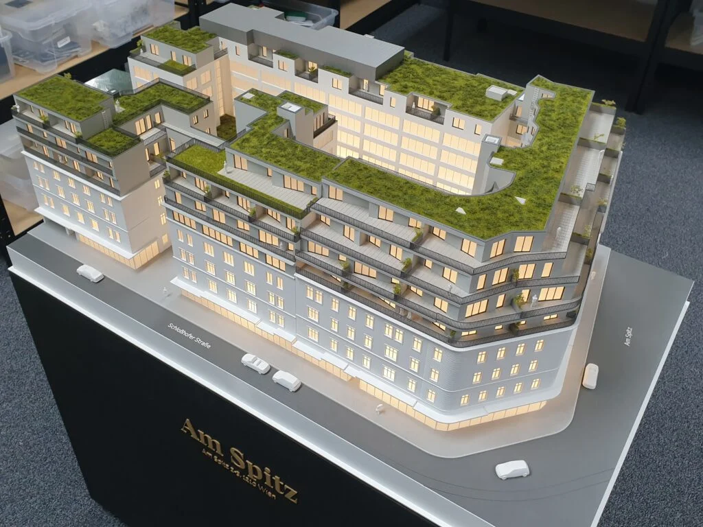 Architekturmodell Immobilien 1:100 – Wohnhaus Am Spitz mit begrünten Dächern, Innenhof und beleuchteten Wohnungen.