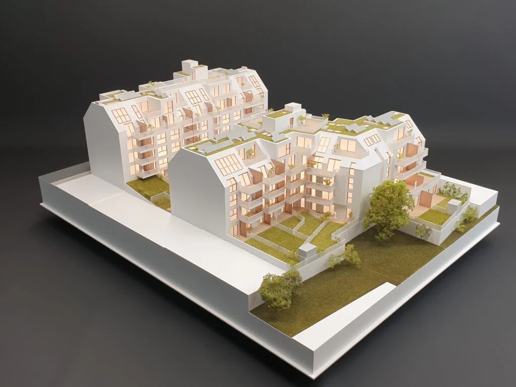 Architekturmodell Immobilien 1:100 – Wohnanlage mit Dachbegrünung, Innenhöfen und beleuchteten Wohnungen.