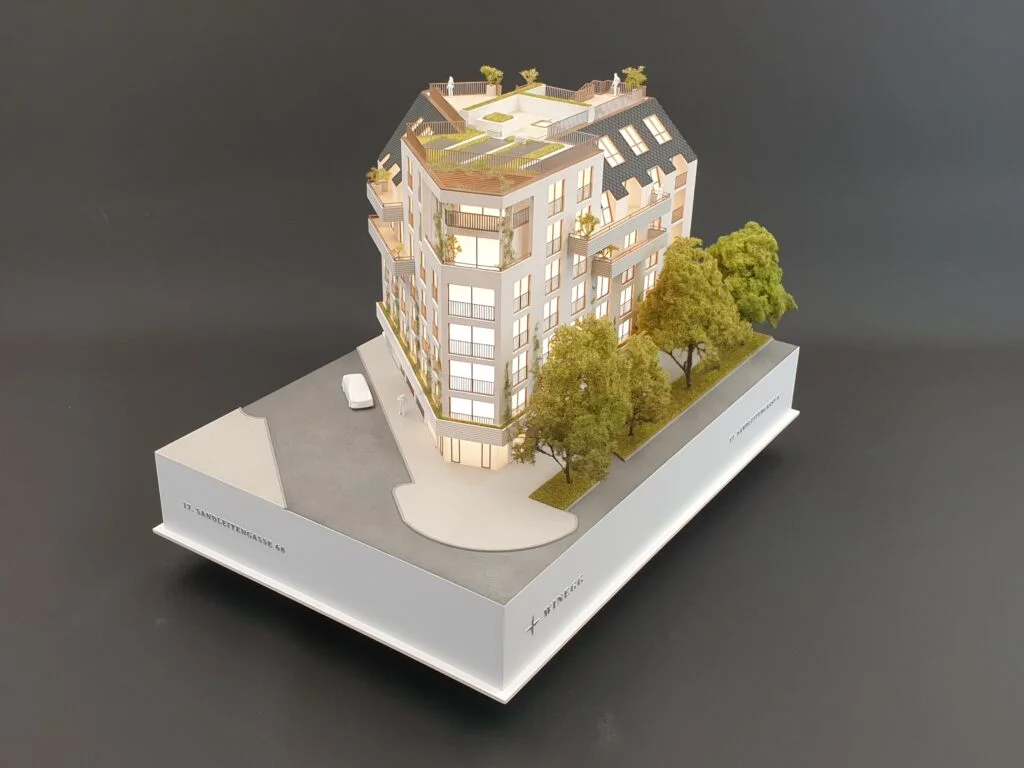Architekturmodell Immobilien 1:100 – Eckwohnhaus mit begrünten Dachterrassen, Balkonen und Beleuchtung.