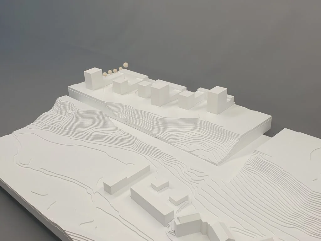 Umgebungsmodell – weiße Baukörper mit Höhenlinien und Hanglage, Darstellung von Gebäuden im topografischen Kontext.