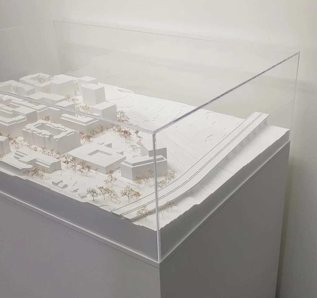 Umgebungsmodell – Stadtquartier mit weißen Baukörpern, Straßen, Bäumen und Acrylglasabdeckung für Wettbewerbspräsentation.