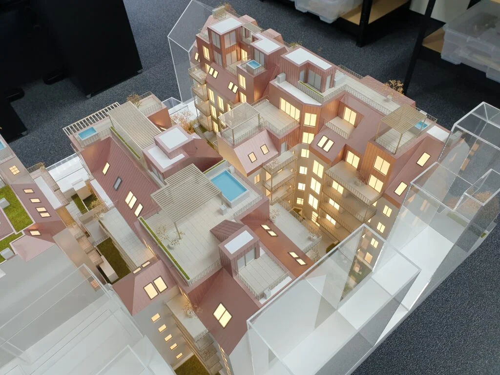 Architekturmodell Wohnquartier mit LED-Beleuchtung, roten Dachflächen, Innenhof, Fassadendetails und integriertem Poolbereich.