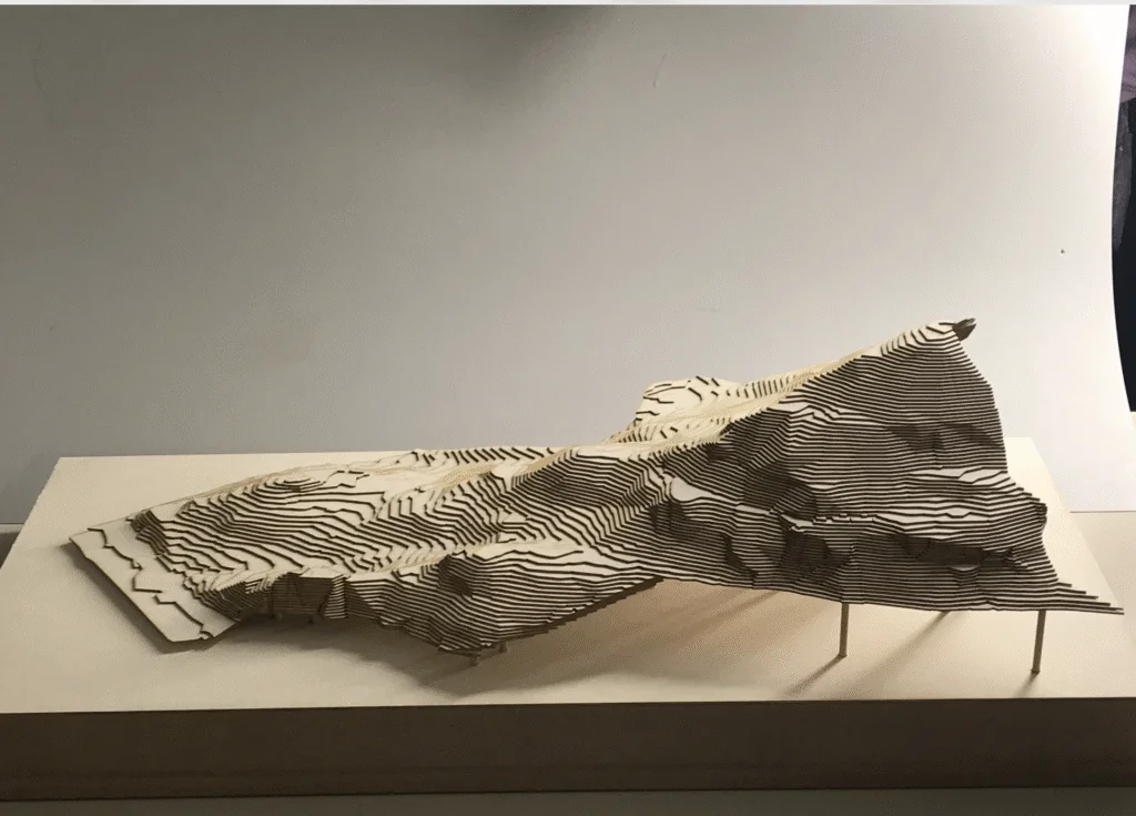 Landschaftsmodell aus Holzschichten – topografische Darstellung mit Höhenlinien und Geländeverlauf.