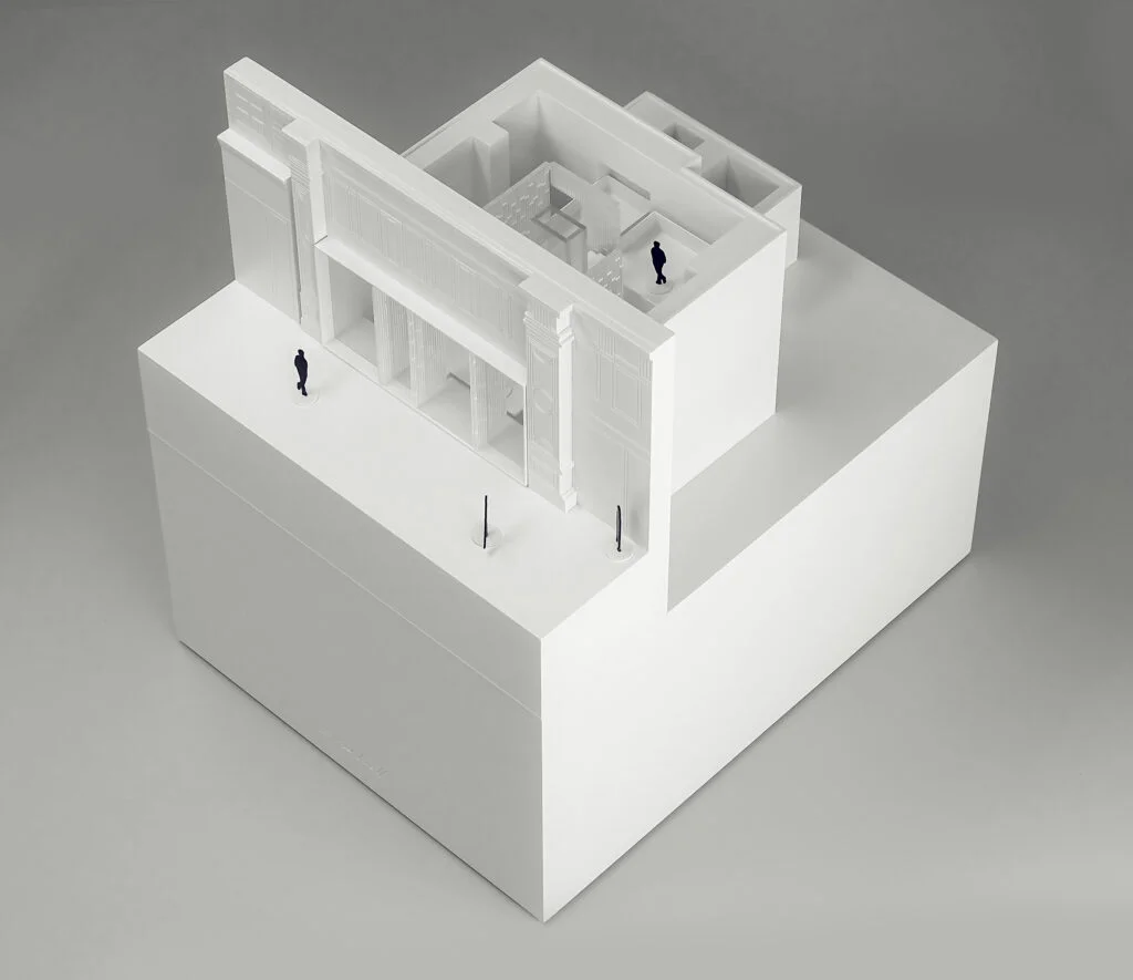 Architekturmodell Stadtgebäude – weiße Fassade mit Säulen, Innenraumdarstellung und minimalistischer Stadtraum.