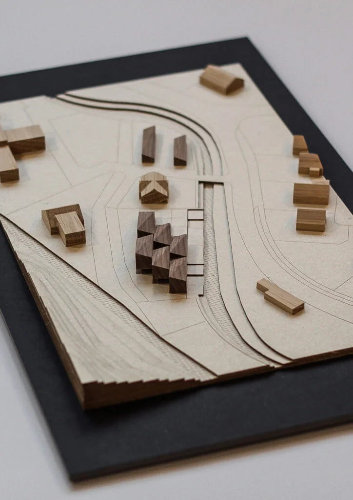 Architekturmodell aus Holz – Bebauungsstudie mit abstrahierten Gebäuden, Straßenführung und Geländeformen.