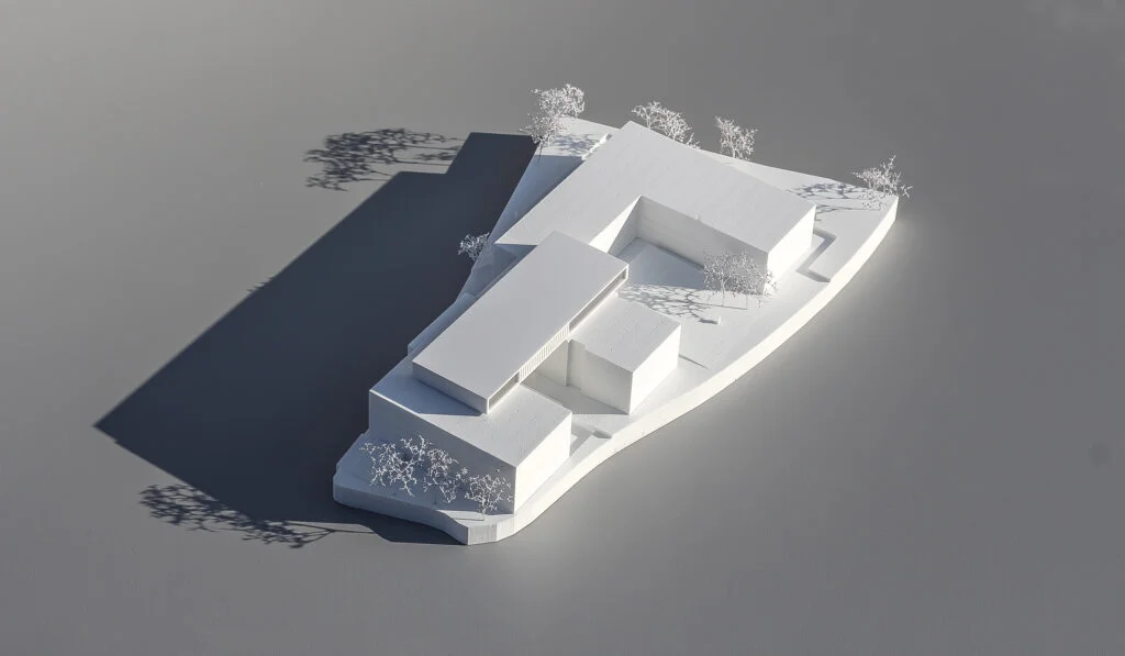 Architekturmodell 1:500 – reduziertes Wettbewerbsmodell eines Gebäudekomplexes mit klaren Volumen und Bäumen.