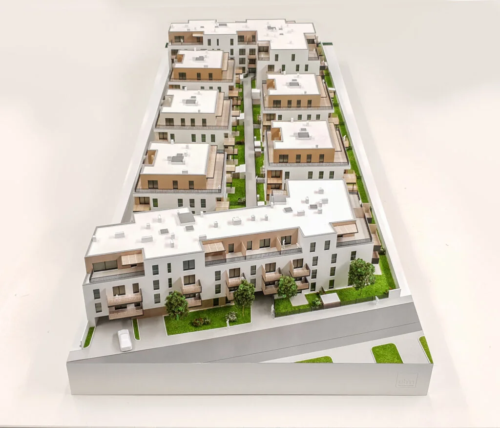 Architekturmodell 1:100 – realistische Wohnanlage mit Gebäuden, Grünflächen und Zufahrtswegen, ideal für Präsentationen.