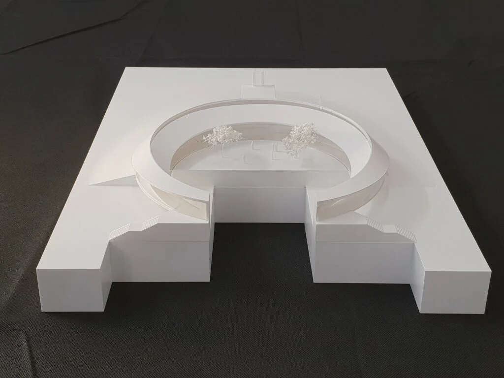 Wettbewerbsmodell 1:500 – ringförmiges Gebäude mit Innenhof und minimalistisch dargestellter Begrünung.