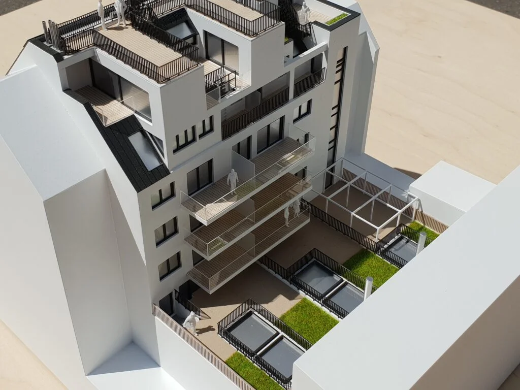 Vollfarbiges Architekturmodell – Wohnhaus mit Balkonen, Dachterrassen und begrünten Innenhöfen.