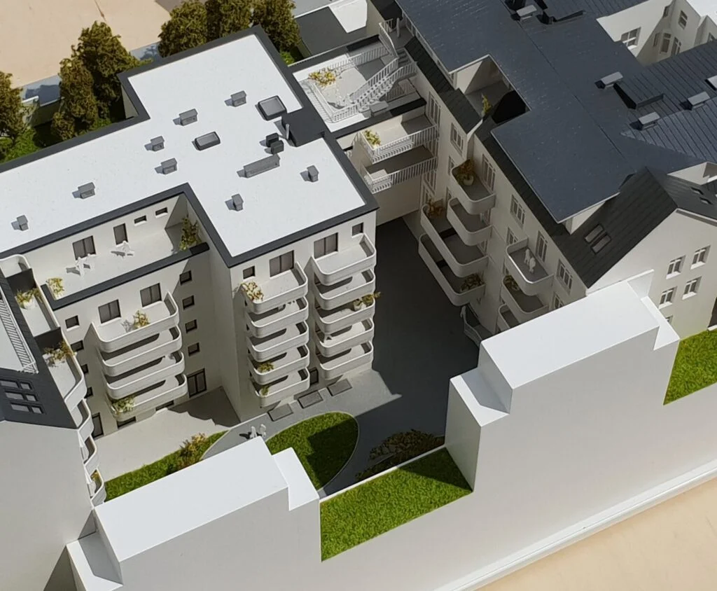 Architekturmodell 1:100 – Wohnblock mit Innenhof, Balkonen und Dachterrassen, detailreich und realistisch dargestellt.
