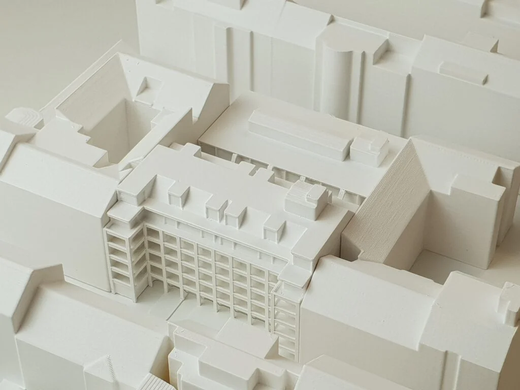 Homogenes Architekturmodell – Blockrandbebauung mit Innenhof, abstrahiert in Weiß mit klaren Baukörpern und Volumen.