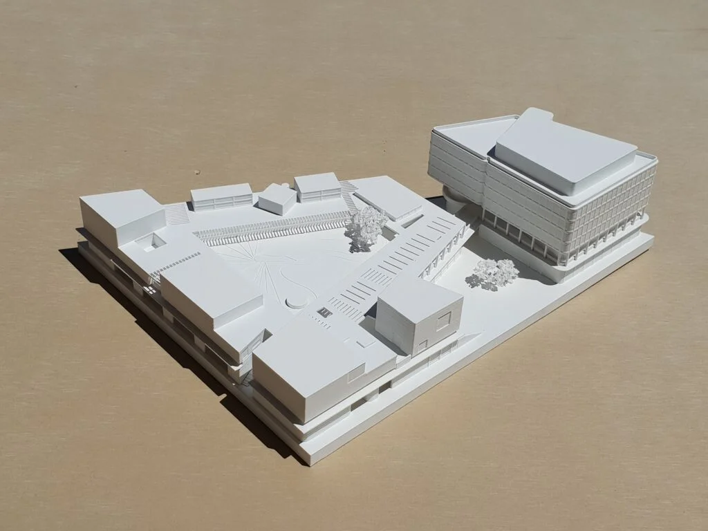 Wettbewerbsmodell 1:500 – Campusgebäude mit Hauptbau, umliegenden Baukörpern, Wegen und Bäumen.