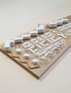 Architekturmodell Wohnquartier – Holzsockel mit weißen Baukörpern und Bäumen, Darstellung von städtebaulichen Strukturen.