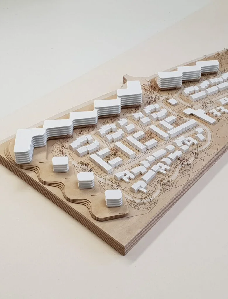 Architekturmodell Wohnquartier – Holzsockel mit weißen Baukörpern und Bäumen, Darstellung von städtebaulichen Strukturen.