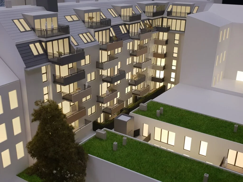 Architekturmodell Wohnhaus – Immobilienmodell mit Balkonen, Innenhof, Grünflächen und stimmungsvoller LED-Beleuchtung.