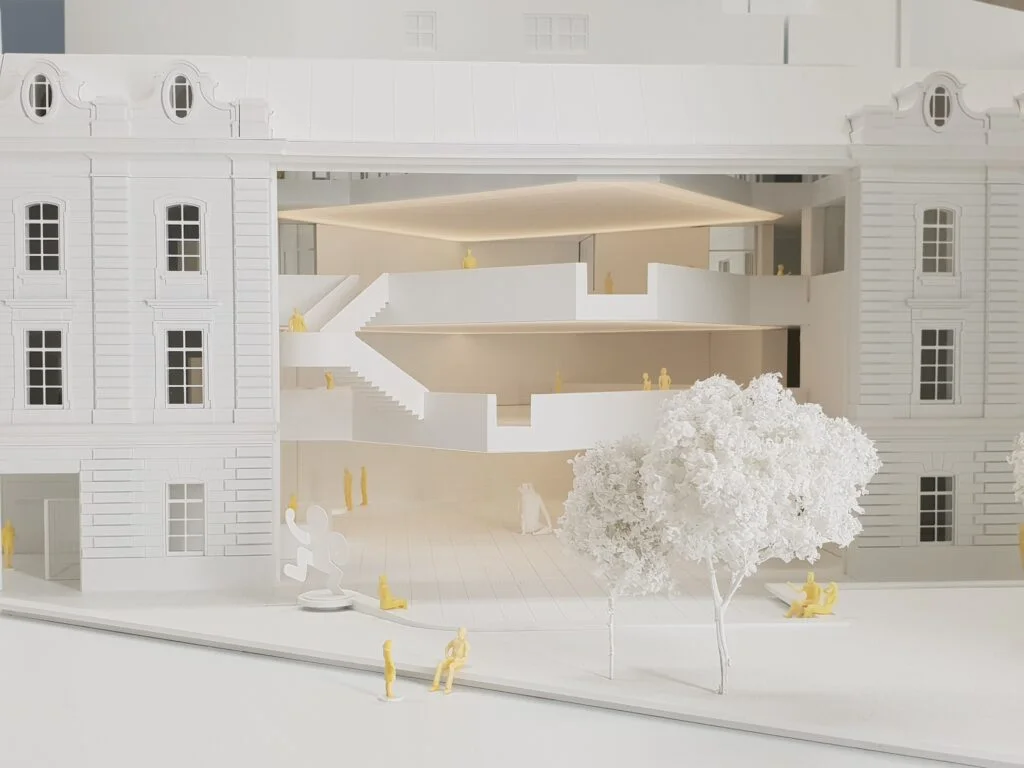 Architektur-Schnittmodell mit klassischer Fassade, offenem Innenraum, Treppenanlagen und modernem Atrium.