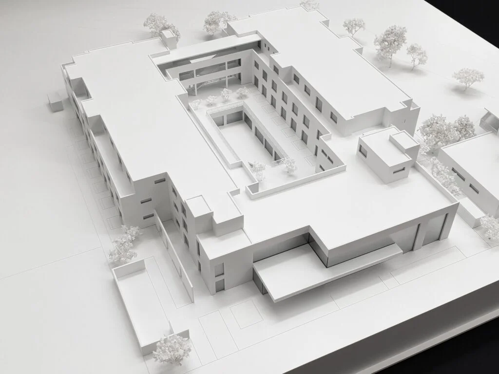 Аrchitekturmodell Wohnkomplex 1:200 – Wettbewerbsmodell in Weiß mit Innenhof, klarer Baukörperdarstellung und abstrahierter Umgebung.