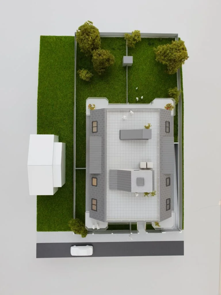 Vollfarbiges Architekturmodell – Wohnhaus mit Dachterrasse, Innenhof und Grünflächen.