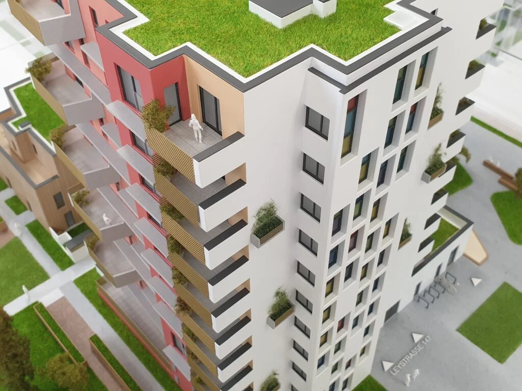 Architekturmodell eines Hochhauses mit begrüntem Dach, Balkonen und farbig gestalteter Fassade.