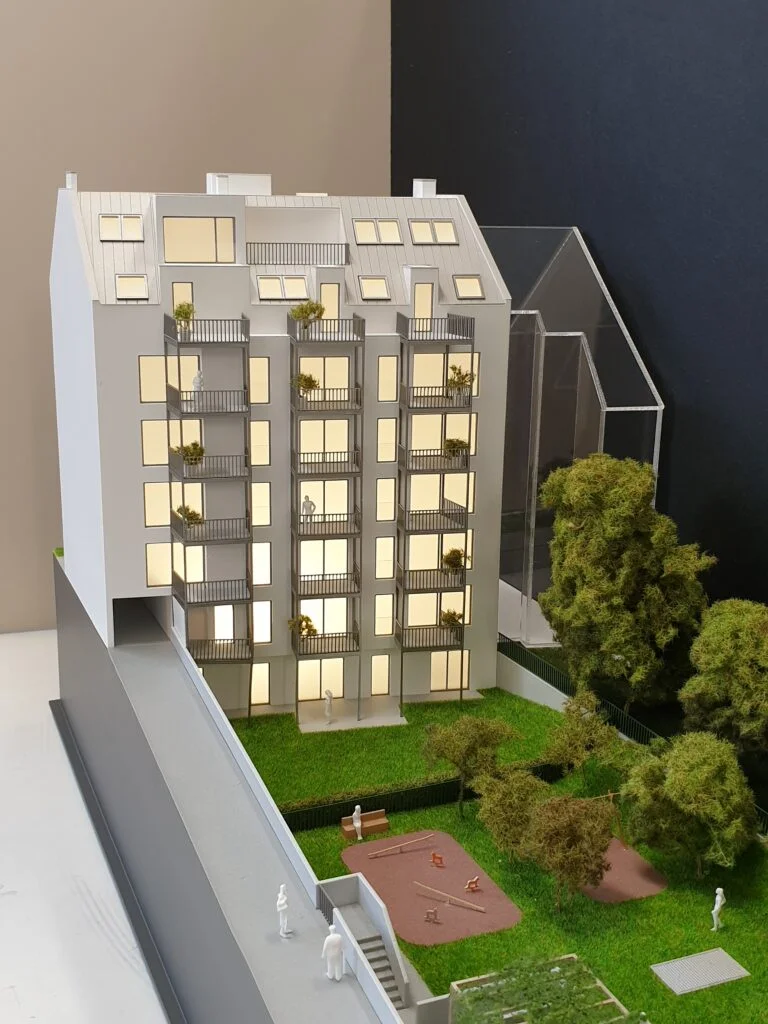 Architekturmodell Wohnhaus – Immobilienmodell mit Beleuchtung, Balkonen, Grünflächen und integriertem Spielplatz.