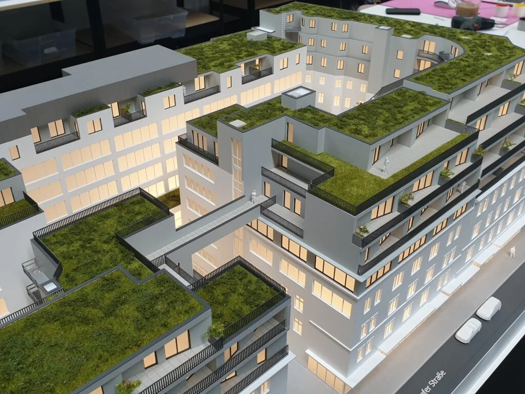 Architekturmodell Wien – Immobilienmodell im Maßstab 1:100, Wohnhaus mit begrünten Dachterrassen, filigranen Balkonen und Steg-Verbindung zwischen Gebäudeteilen.