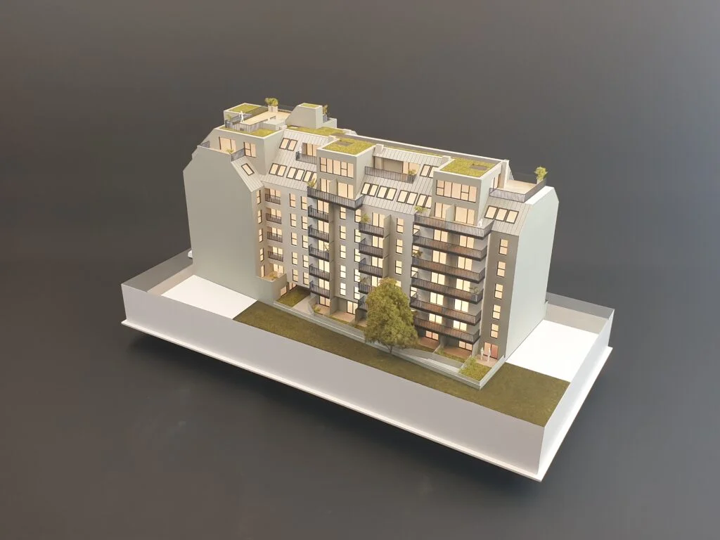 Architekturmodell 1:100 – modernes Mehrfamilienhaus mit Balkonen, Dachgärten und detailreicher Fassadengestaltung.