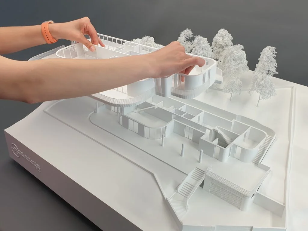 Funktionsmodell moderne Villa mit abnehmbarem Dachgeschoss, detaillierten Innenräumen und umgebender Landschaft mit Bäumen.
