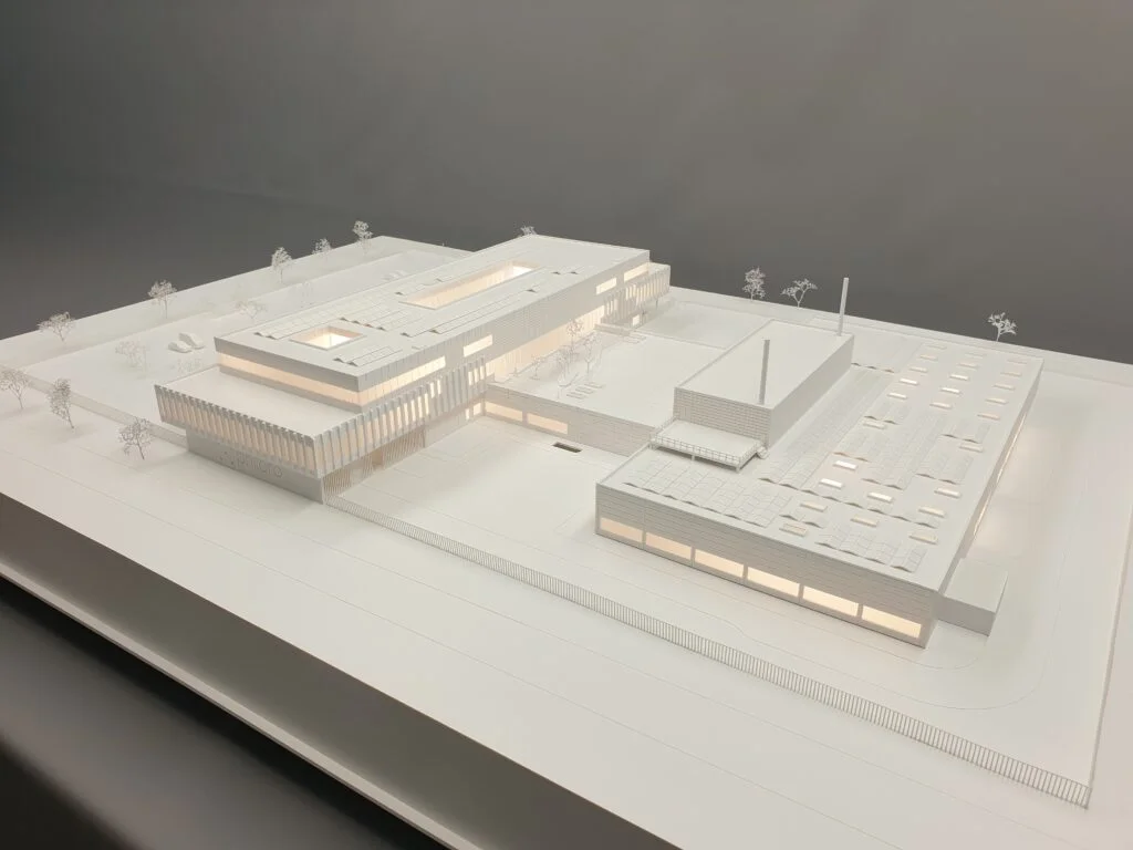 Architekturmodell Industrie 1:200 – Wettbewerbsmodell in Weiß mit klarer Beleuchtung, Fassadendetails und teils aus Holz gefertigten Elementen.