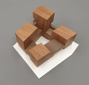Architekturmodell aus Holz – minimalistische Baukörper als Quader, platziert auf weißem Sockel.