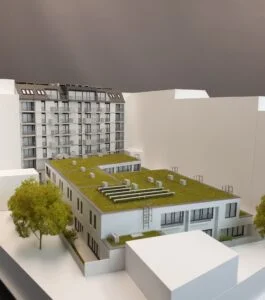 Immobilienmodell 1:100 – moderner Wohnhauskomplex mit begrünten Flachdächern, Balkonen und naturgetreuer Umgebungsdarstellung.
