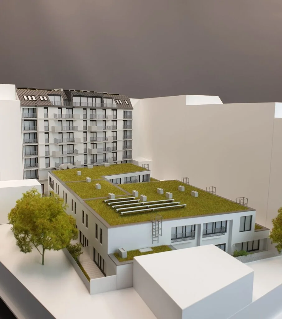 Immobilienmodell 1:100 – moderner Wohnhauskomplex mit begrünten Flachdächern, Balkonen und naturgetreuer Umgebungsdarstellung.
