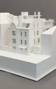 Architekturmodell – Wohnhaus mit historischer Fassade, Dachaufstockung und homogener Darstellung mit stilisierten Bäumen.
