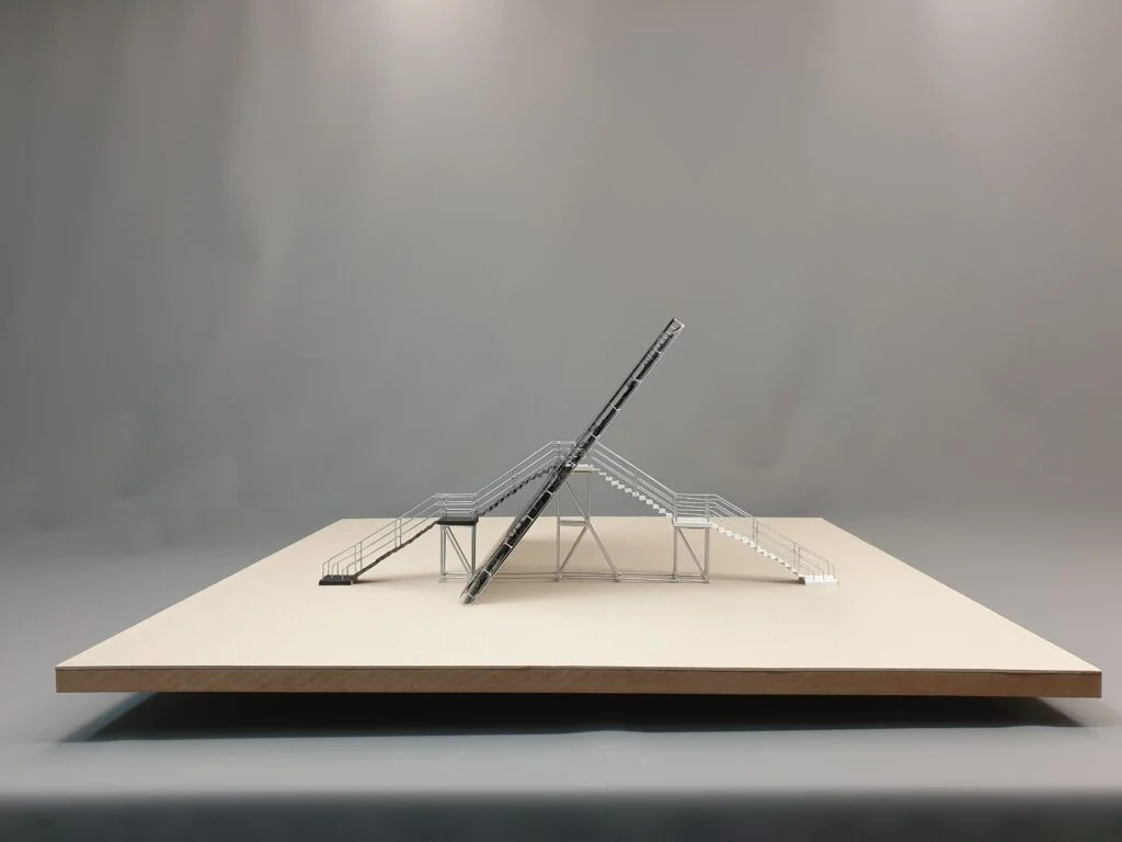 Metallmodell – architektonische Struktur mit Treppenaufgängen, Plattform und geneigtem Konstruktionselement.