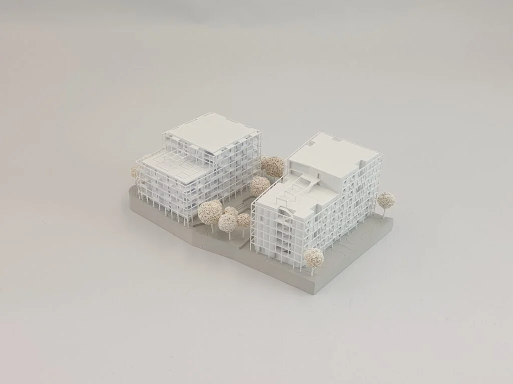 Wettbewerbsmodell 1:500 – modernes Wohnensemble mit klarer Fassadenstruktur, Innenhof und Bäumen im Umfeld.