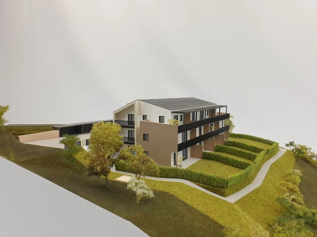 Architekturmodell – Wohnanlage am Hang mit modernen Gebäuden, begrünten Terrassen, Gartenbereichen und klarer Linienführung.