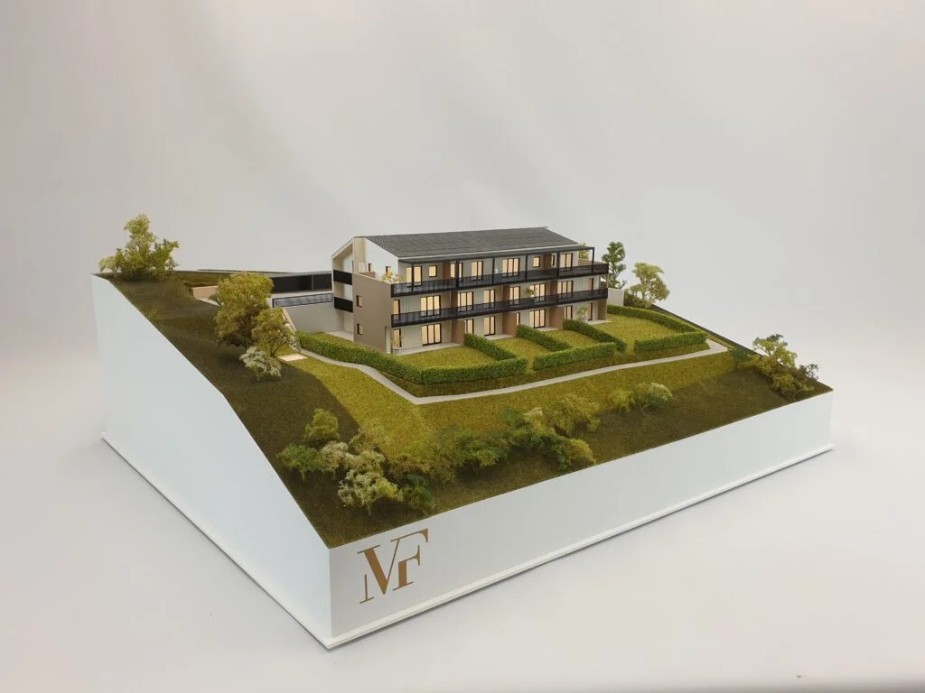 Verkaufsmodell eines modernen Wohnhauses – Architekturmodell mit Holz- und Putzfassade, Terrassen, Balkonen und begrünten Außenflächen.