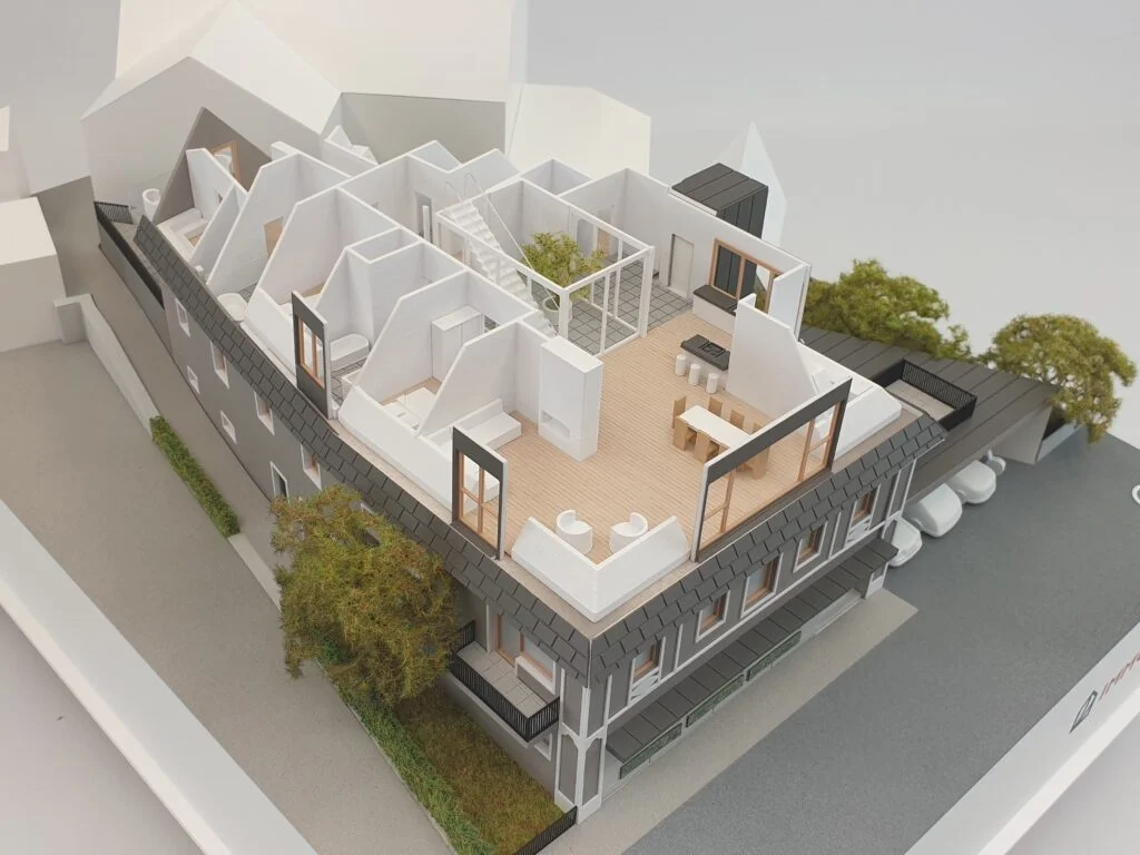Architekturmodell mit offenen Elementen – Wohngebäude mit sichtbaren Innenräumen, Dachgeschossen und Grünflächen.