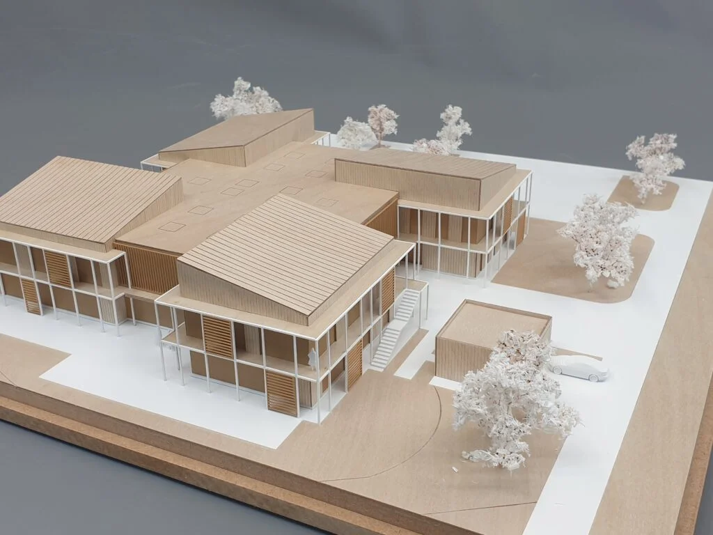 Homogenes Architekturmodell – moderner Holzbau mit Flachdächern, offenen Fassaden und abstrahierten Bäumen.