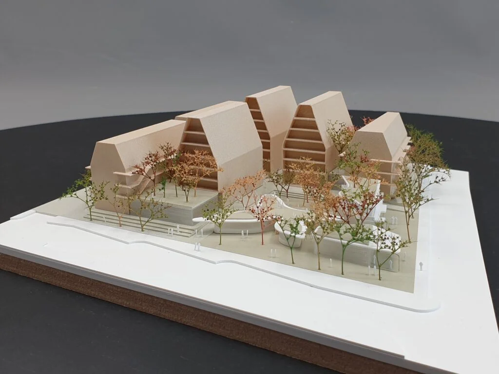 Wettbewerbsmodell 1:500 – Wohngebäude mit markanter Dachform, Holzoptik und detaillierter Begrünung.