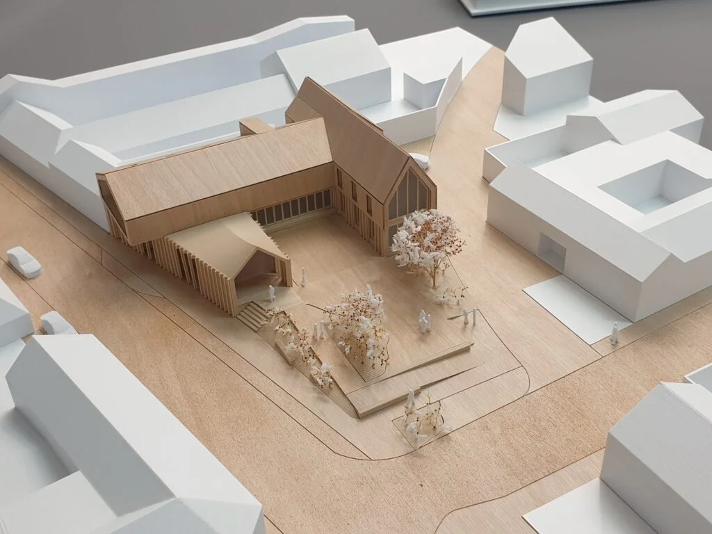 Architekturmodell Holzbau – Gebäude mit markantem Eingangsbereich, Bäumen und Platzgestaltung im städtebaulichen Kontext.