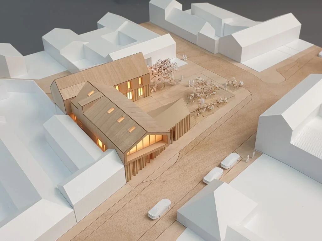 : Architekturmodell Dorfzentrum – Wettbewerbsmodell in Holzbauweise mit offenen Fassaden, begrünten Plätzen und städtebaulichem Kontext.