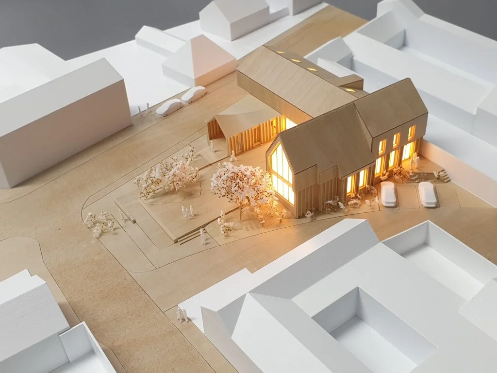 Architekturmodell Wohnhaus 1:200 – Modell mit Holzelementen, Innenhof, Bäumen und stimmungsvoller Beleuchtung.