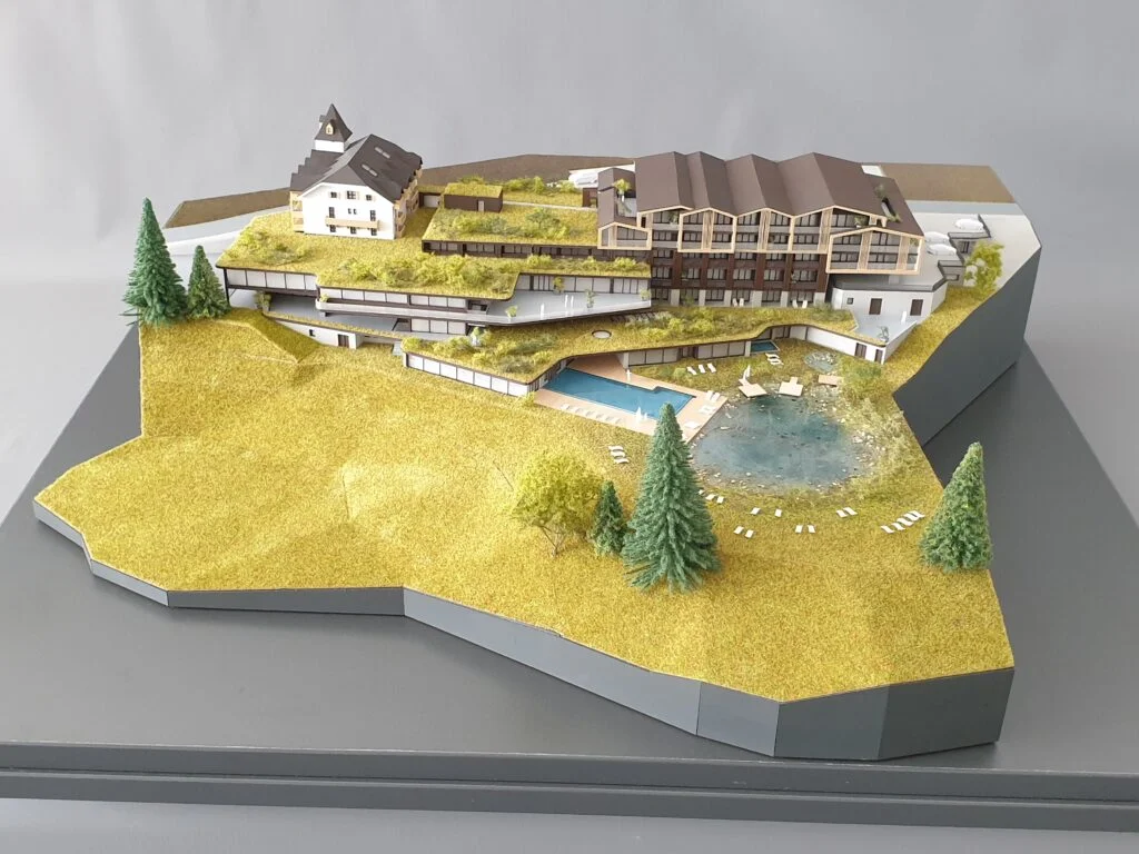 Architekturmodell Hotel 1:200 – alpines Bergresort mit Schwimmteich, Hanglage, Landschaft und teils aus Holz gefertigten Details.