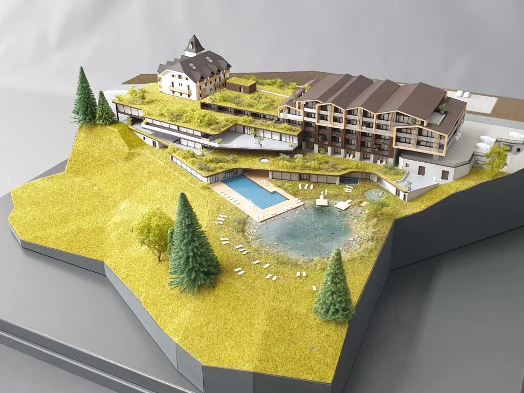 : Vollfarbiges Architekturmodell 1:200 – Hotelanlage mit Altbau, Neubau, Pool und Landschaft.