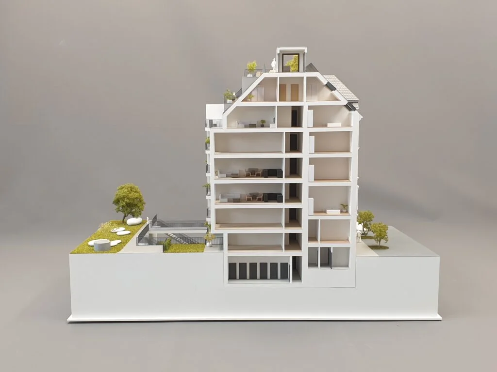 Architekturmodell Querschnitt – Mehrfamilienhaus mit Wohnungen, begrünten Außenflächen und präziser Innenraumdarstellung.