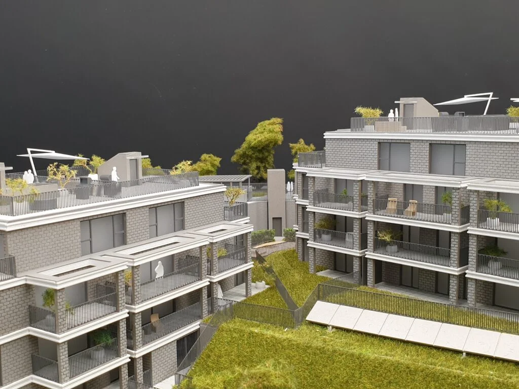 Verkaufsmodell eines Mehrfamilienhauses mit Fassaden in Ziegeloptik, großen Balkonen und begrünten Dachterrassen – detailreiches Immobilienmodell für den Verkauf.