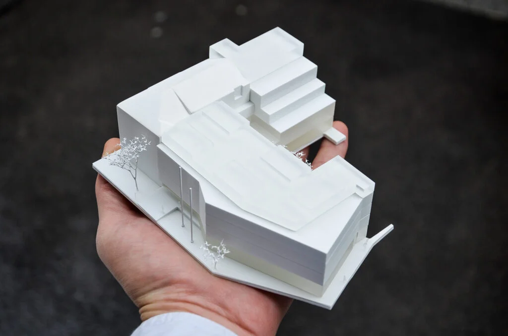 Wettbewerbsmodell 1:500 – handgehaltenes Architekturmodell eines Gebäudes mit klaren Baukörpern.