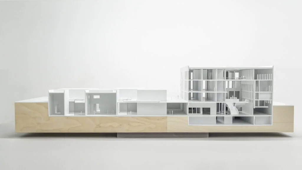 Architekturmodell Querschnitt – modernes Gebäude mit mehrstöckigen Ebenen, weißen Strukturen und Holzsockel.